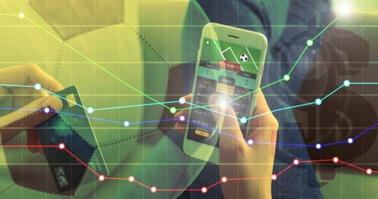 Man Holds Cell Phone With Sports Betting App and Finacial Line Graph Image Overlay