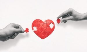 Black & White Hands Place Missing Red Pieces of Heart Puzzle
