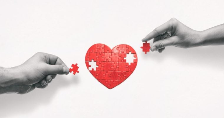 Black & White Hands Place Missing Red Pieces of Heart Puzzle