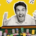 Man Sits In Front of Stacked Poker Chips with Excited Expression