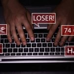 Red Speech Bubbles Display Abusive Language as Man Types on Laptop