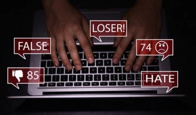 Red Speech Bubbles Display Abusive Language as Man Types on Laptop