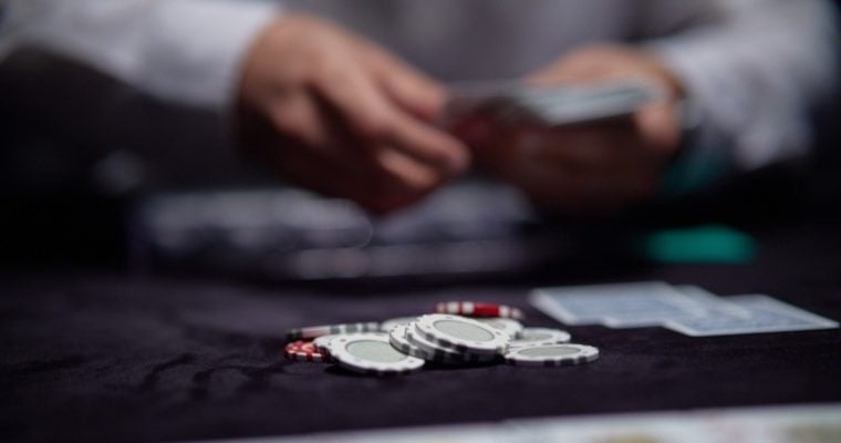 Concept of Poker Game, Live Dealer Dealing Cards with Poker Chips on Game Table
