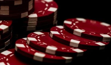 Red and White Poker Chips Stacked and Laying on Black Background