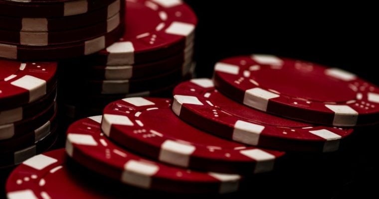 Red and White Poker Chips Stacked and Laying on Black Background