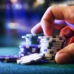 Man Touches Stacks of Blue and White Colored Poker Chips on Green Game Table