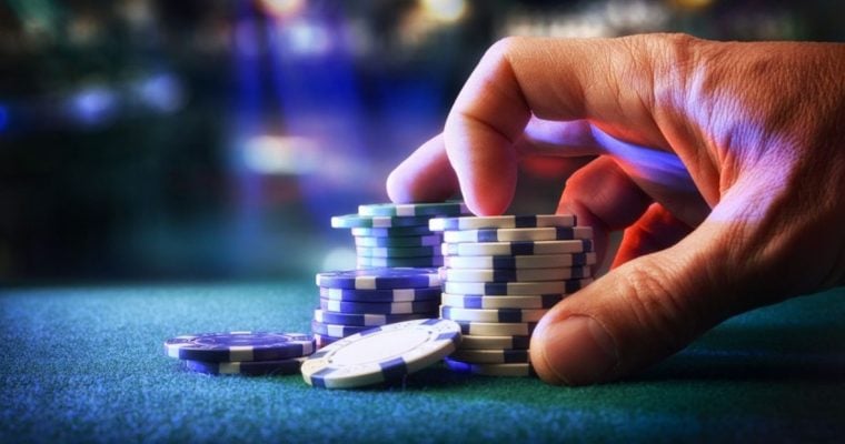 Man Touches Stacks of Blue and White Colored Poker Chips on Green Game Table