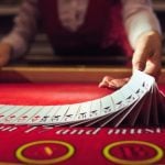 Blackjack Live Dealer Flips Cards on Red Casino Game Table