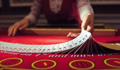 Blackjack Live Dealer Flips Cards on Red Casino Game Table