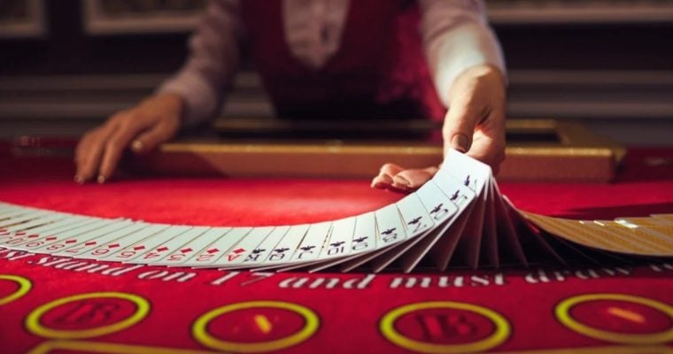 Blackjack Live Dealer Flips Cards on Red Casino Game Table