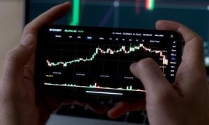 Man Uses Smartphone to Check Rising Financial Graph