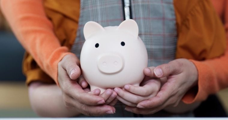 Adult Holds Child's Hands As They Hold Porcelain Piggy Bank
