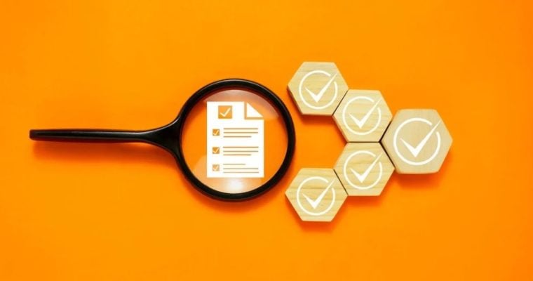 Magnifying Glass Sits Over Survey Document with White Checks on Wooden Blocks