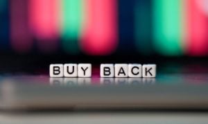 Buy Back Spelled Out in Tiny White Blocks Against Blurred Financial Graph in Background