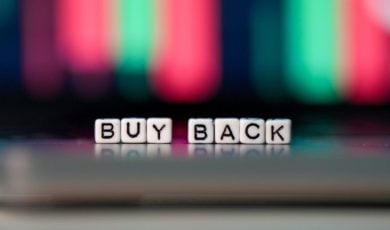 Buy Back Spelled Out in Tiny White Blocks Against Blurred Financial Graph in Background