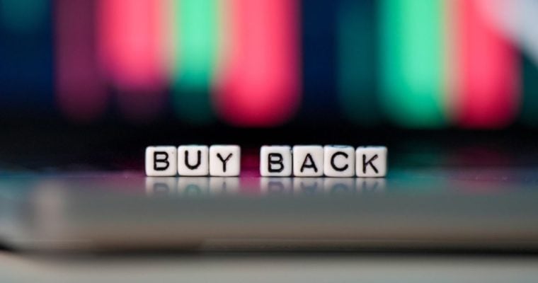 Buy Back Spelled Out in Tiny White Blocks Against Blurred Financial Graph in Background