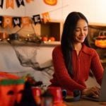 Woman Uses Laptop Inside Living Room with Halloween Decor