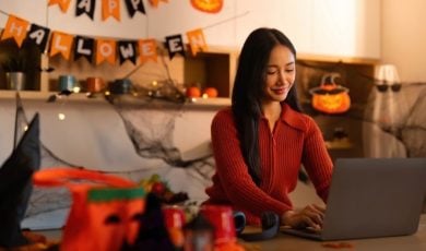 Woman Uses Laptop Inside Living Room with Halloween Decor