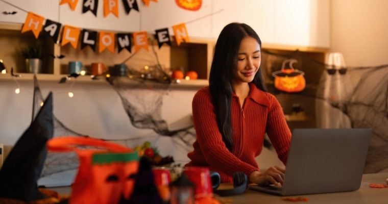 Woman Uses Laptop Inside Living Room with Halloween Decor